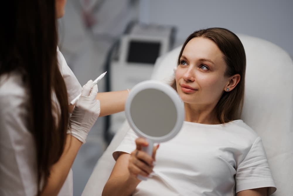 Advanced facial consultation at The Zen Den, where a client discusses treatment options with a professional while reviewing results in a mirror.