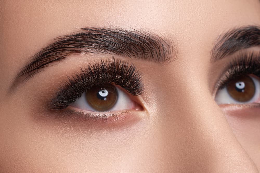 Close-up of a woman’s eyes with full, voluminous eyelash extensions and perfectly shaped eyebrows, showcasing the All Eyes on You treatment at The Zen Den.