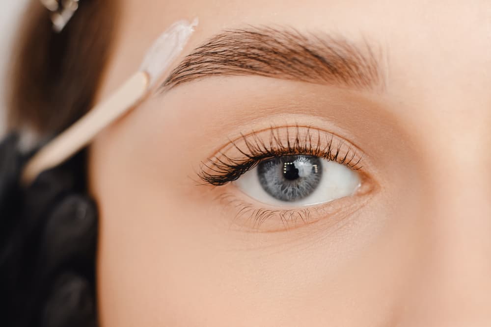 Close-up of a woman’s eye during a brow wax and tint treatment, showing precise product application for well-shaped, defined eyebrows at The Zen Den.