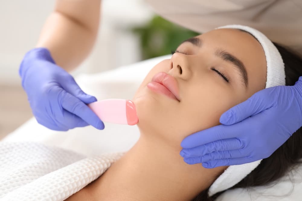 Woman receiving a chin wax treatment at The Zen Den, performed by a therapist wearing purple gloves, ensuring smooth and hair-free skin.
