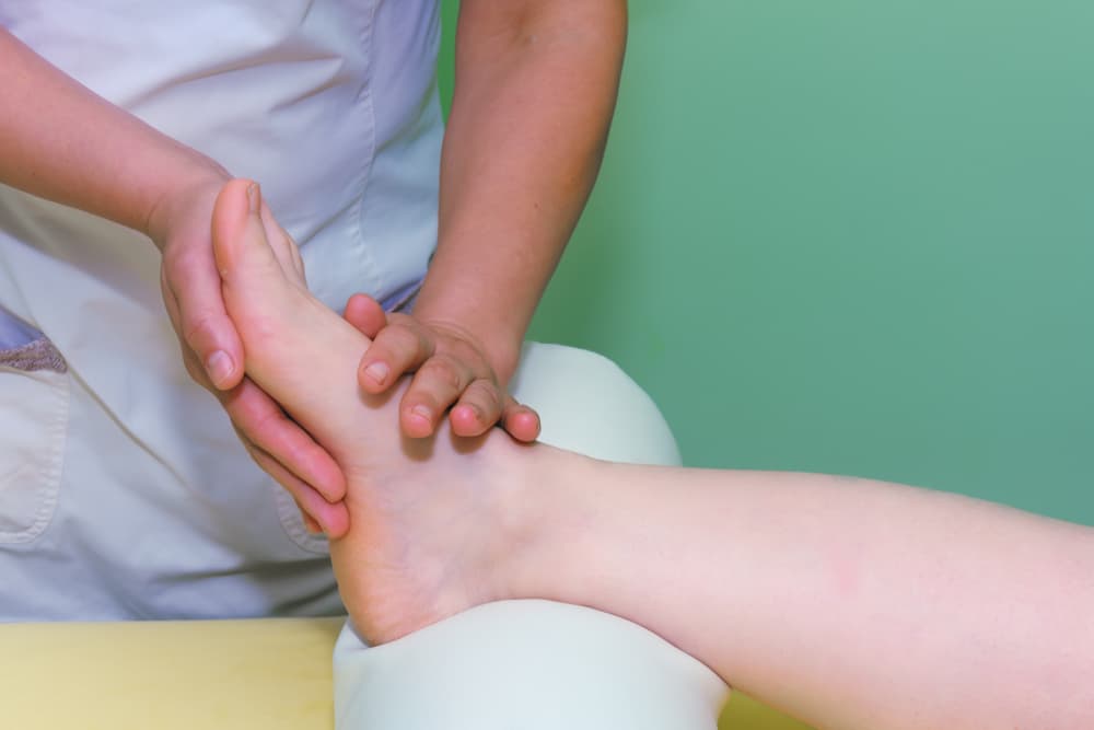 Close-up of a therapist gently massaging a client’s foot during an oncology massage therapy session at The Zen Den, focusing on comfort, relaxation, and safe touch for those with specific health needs.