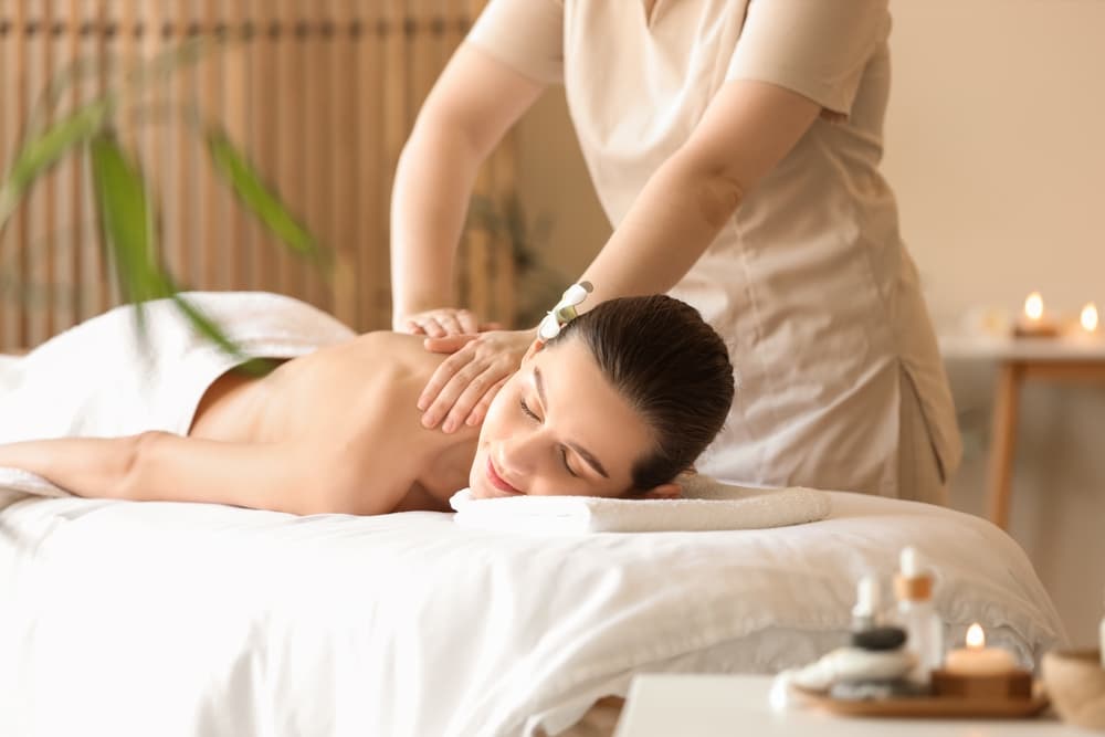 Woman enjoying a relaxing back massage at The Zen Den spa in Glasgow, with soft lighting and a calming atmosphere.