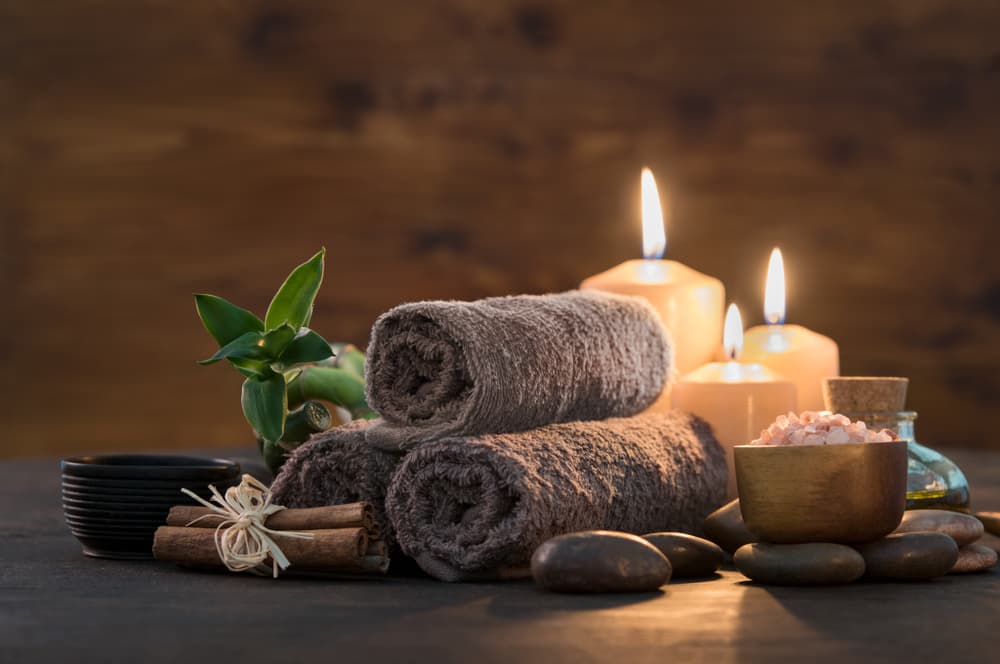 Spa setting with rolled towels, candles, and Himalayan salts creating a calming atmosphere, representing the Watt A Wellness Pass at The Zen Den in Glasgow.